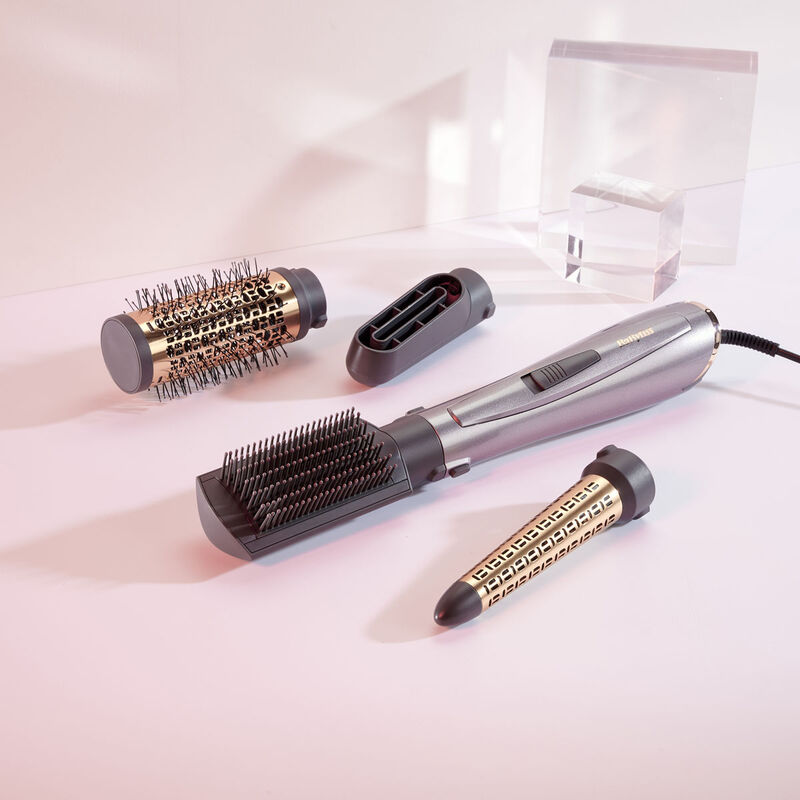 Air Style 1000 and 4 styling heads (50mm thermal brush, paddle brush, drying nozzle, curling attachment) on flat surface